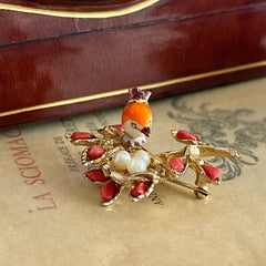 Vintage Swoboda bird nest brooch with a painted bone bird, faux pearl eggs, coral‑colored stone chips, and gold‑tone metal branch detailing.
