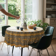 Round coated cotton tablecloth in sunny yellow and deep blue, featuring alternating Provençal floral and geometric bands