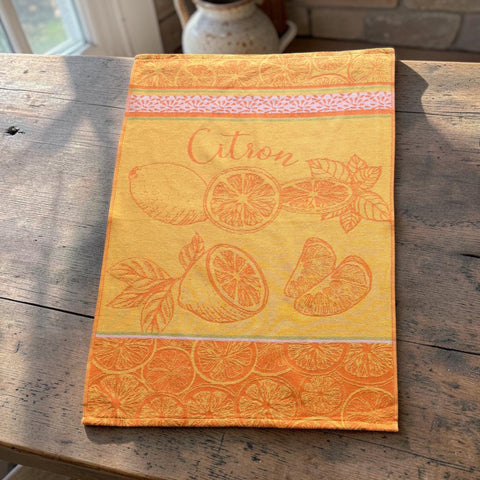 Yellow and orange French tea towel with woven lemon and citrus slice motifs and decorative borders, by Coucke.