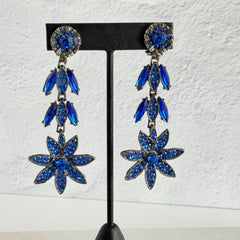 Pair of vintage 1980s Thelma Deutsch clip‑on earrings with deep blue rhinestones in a cascading dangle design set in dark gunmetal‑tone metal.