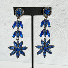 Pair of vintage 1980s Thelma Deutsch clip‑on earrings with deep blue rhinestones in a cascading dangle design set in dark gunmetal‑tone metal.