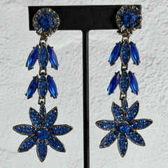Pair of vintage 1980s Thelma Deutsch clip‑on earrings with deep blue rhinestones in a cascading dangle design set in dark gunmetal‑tone metal.