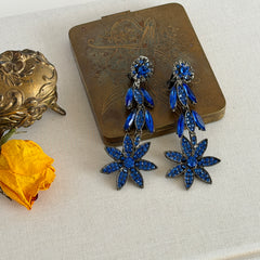 Pair of vintage 1980s Thelma Deutsch clip‑on earrings with deep blue rhinestones in a cascading dangle design set in dark gunmetal‑tone metal.