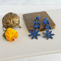 Pair of vintage 1980s Thelma Deutsch clip‑on earrings with deep blue rhinestones in a cascading dangle design set in dark gunmetal‑tone metal.