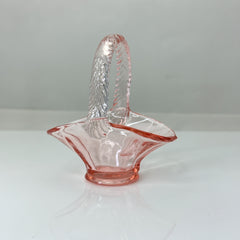 Vintage pink Depression glass favor basket with ruffled rim and twisted handle, styled on a neutral surface with soft natural light.