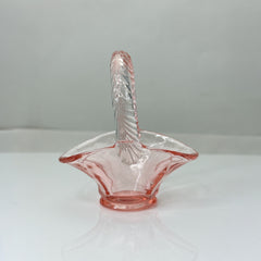 Vintage pink Depression glass favor basket with ruffled rim and twisted handle, styled on a neutral surface with soft natural light.