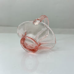 Vintage pink Depression glass favor basket with ruffled rim and twisted handle, styled on a neutral surface with soft natural light.