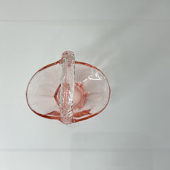 Vintage pink Depression glass favor basket with ruffled rim and twisted handle, styled on a neutral surface with soft natural light.