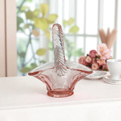 Vintage pink Depression glass favor basket with ruffled rim and twisted handle, styled on a neutral surface with soft natural light.