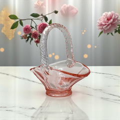 Vintage pink Depression glass favor basket with ruffled rim and twisted handle, styled on a neutral surface with soft natural light.