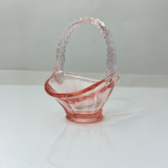 Vintage pink Depression glass favor basket with ruffled rim and twisted handle, styled on a neutral surface with soft natural light.