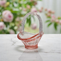 Vintage pink Depression glass favor basket with ruffled rim and twisted handle, styled on a neutral surface with soft natural light.