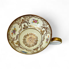 Vintage Tirschenreuth Bavaria demi-tasse and saucer set in cream porcelain with ornate floral clusters and gold scrollwork; footed teacup with gilded handle and rim, saucer marked with crown and shield logo and red glaze number 2284.