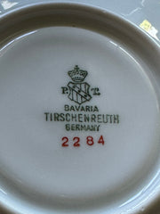 Vintage Tirschenreuth Bavaria demi-tasse and saucer set in cream porcelain with ornate floral clusters and gold scrollwork; footed teacup with gilded handle and rim, saucer marked with crown and shield logo and red glaze number 2284.