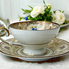 Vintage Tirschenreuth Bavaria demi-tasse and saucer set in cream porcelain with ornate floral clusters and gold scrollwork; footed teacup with gilded handle and rim, saucer marked with crown and shield logo and red glaze number 2284.