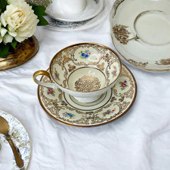 Vintage Tirschenreuth Bavaria demi-tasse and saucer set in cream porcelain with ornate floral clusters and gold scrollwork; footed teacup with gilded handle and rim, saucer marked with crown and shield logo and red glaze number 2284.