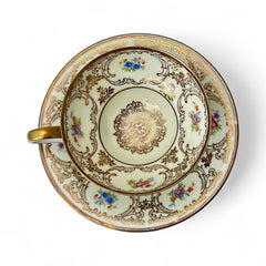 Vintage Tirschenreuth Bavaria demi-tasse and saucer set in cream porcelain with ornate floral clusters and gold scrollwork; footed teacup with gilded handle and rim, saucer marked with crown and shield logo and red glaze number 2284.