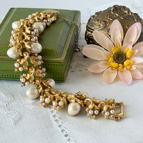 Vintage gold‑tone Tortolani bracelet featuring ornate sculpted floral panels with raised faux pearl clusters and a wide mid‑century silhouette.