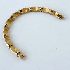 Vintage 1960s Trifari Crown sapphire blue rhinestone birthstone bracelet with brushed gold tone ribbon links and fold‑over clasp.