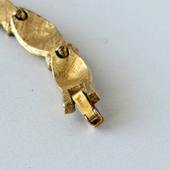 Vintage 1960s Trifari Crown sapphire blue rhinestone birthstone bracelet with brushed gold tone ribbon links and fold‑over clasp.