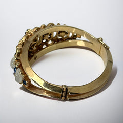 Vintage Trifari “Clair de Lune” bracelet by Alfred Philippe, gold-plated hinged bangle with crescent-shaped opalized faux moonstones, sapphire blue and clear rhinestones, shown in various lighting and angles to highlight design and craftsmanship