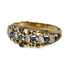 Vintage Trifari “Clair de Lune” bracelet by Alfred Philippe, gold-plated hinged bangle with crescent-shaped opalized faux moonstones, sapphire blue and clear rhinestones, shown in various lighting and angles to highlight design and craftsmanship