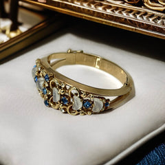 Vintage Trifari “Clair de Lune” bracelet by Alfred Philippe, gold-plated hinged bangle with crescent-shaped opalized faux moonstones, sapphire blue and clear rhinestones, shown in various lighting and angles to highlight design and craftsmanship