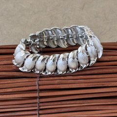 Vintage Trifari Crown silver‑tone bracelet with sculptural brushed and polished links, photographed on botanical paper and wood background.