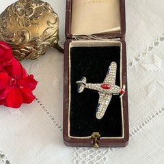 Vintage Trifari airplane brooch with clear stones, red nose detail, and blue enamel accents.