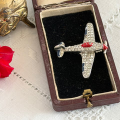 Vintage Trifari airplane brooch with clear stones, red nose detail, and blue enamel accents.