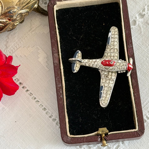 Vintage Trifari airplane brooch with clear stones, red nose detail, and blue enamel accents.