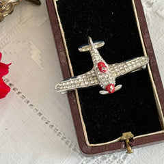 Vintage Trifari airplane brooch with clear stones, red nose detail, and blue enamel accents.