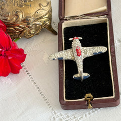 Vintage Trifari airplane brooch with clear stones, red nose detail, and blue enamel accents.
