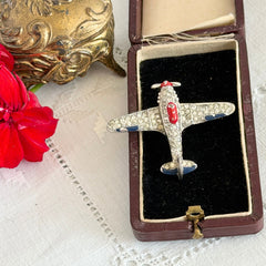 Vintage Trifari airplane brooch with clear stones, red nose detail, and blue enamel accents.