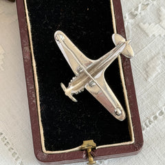 Vintage Trifari airplane brooch with clear stones, red nose detail, and blue enamel accents.