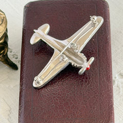 Vintage Trifari airplane brooch with clear stones, red nose detail, and blue enamel accents.