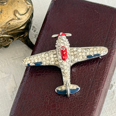 Vintage Trifari airplane brooch with clear stones, red nose detail, and blue enamel accents.