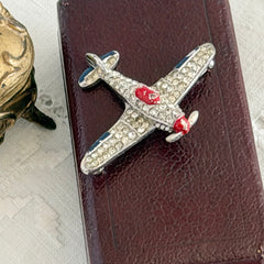 Vintage Trifari airplane brooch with clear stones, red nose detail, and blue enamel accents.