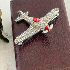 Vintage Trifari airplane brooch with clear stones, red nose detail, and blue enamel accents.