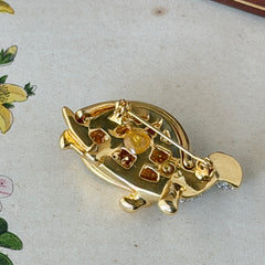 Vintage gold tone turtle brooch with green enamel shell and clear rhinestones, viewed from front and back.