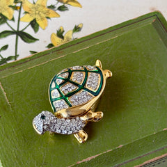 Vintage gold tone turtle brooch with green enamel shell and clear rhinestones, viewed from front and back.
