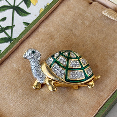 Vintage gold tone turtle brooch with green enamel shell and clear rhinestones, viewed from front and back.