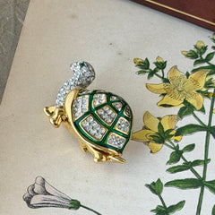 Vintage gold tone turtle brooch with green enamel shell and clear rhinestones, viewed from front and back.