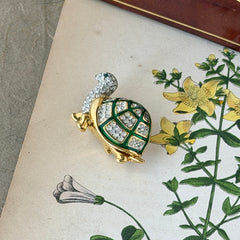 Vintage gold tone turtle brooch with green enamel shell and clear rhinestones, viewed from front and back.