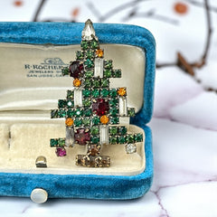 Vintage 1950s Christmas tree brooch with green, red, amber, and clear rhinestones in a gold tone setting, featuring five candle-like stones and a teardrop topper; unsigned Weiss style, very good condition.