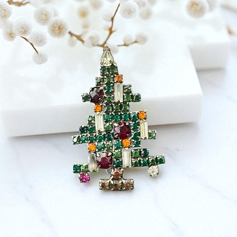 Vintage 1950s Christmas tree brooch with green, red, amber, and clear rhinestones in a gold tone setting, featuring five candle-like stones and a teardrop topper; unsigned Weiss style, very good condition.