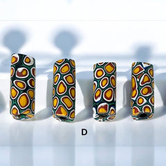 A set of vintage Venetian millefiori African trade beads in vibrant green and yellow. The tube-shaped glass beads, originating from Ghana, feature intricate floral patterns and showcase the rich history of 19th and 20th-century trade. Some beads show minor chips due to age, adding to their authentic vintage charm.