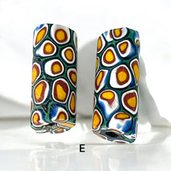 A set of vintage Venetian millefiori African trade beads in vibrant green and yellow. The tube-shaped glass beads, originating from Ghana, feature intricate floral patterns and showcase the rich history of 19th and 20th-century trade. Some beads show minor chips due to age, adding to their authentic vintage charm.