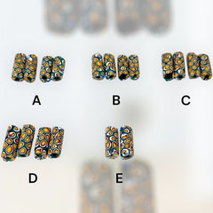 A set of vintage Venetian millefiori African trade beads in vibrant green and yellow. The tube-shaped glass beads, originating from Ghana, feature intricate floral patterns and showcase the rich history of 19th and 20th-century trade. Some beads show minor chips due to age, adding to their authentic vintage charm.