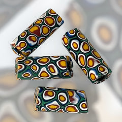 A set of vintage Venetian millefiori African trade beads in vibrant green and yellow. The tube-shaped glass beads, originating from Ghana, feature intricate floral patterns and showcase the rich history of 19th and 20th-century trade. Some beads show minor chips due to age, adding to their authentic vintage charm